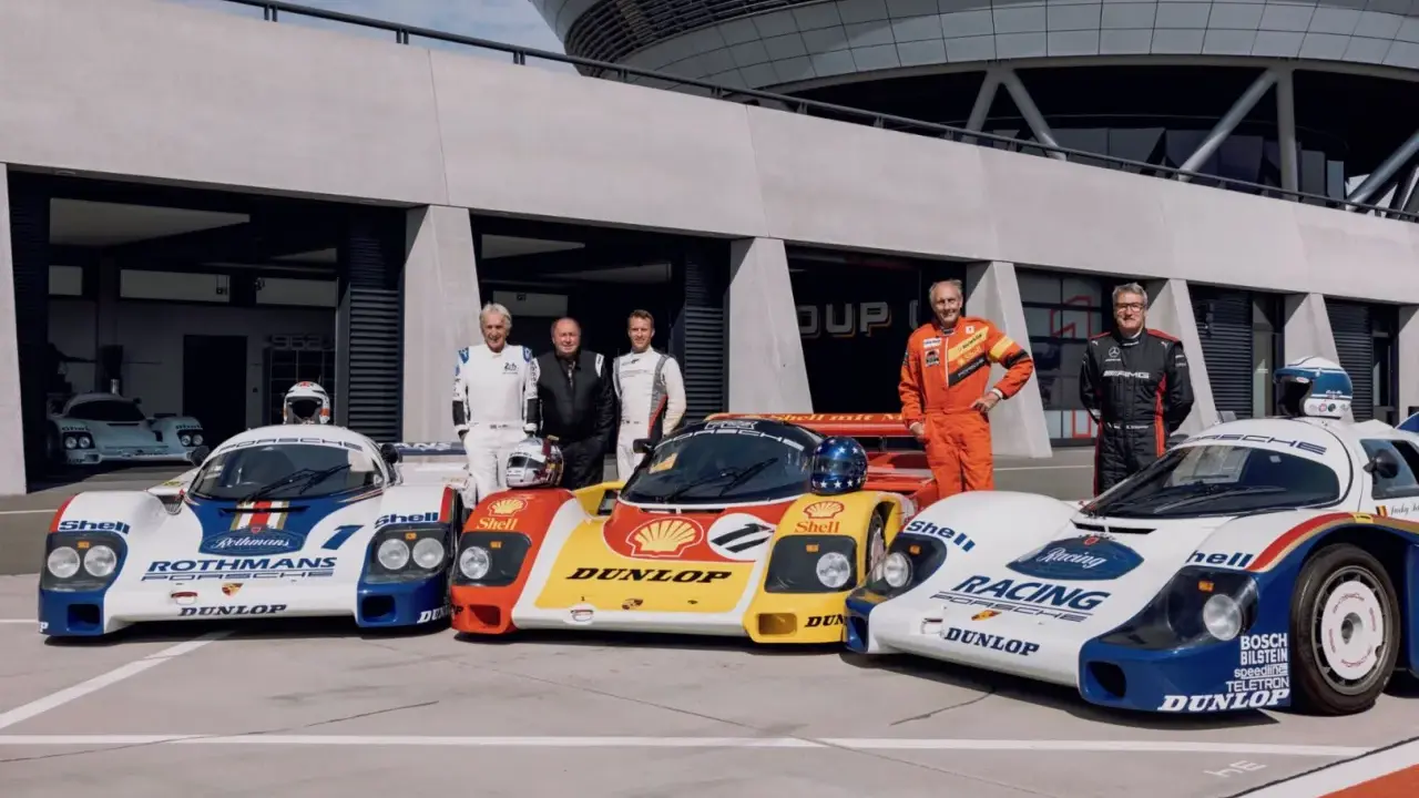 Fünf Rennfahrer stehen stolz neben ihren Porsche-Rennwagen der Gruppe C.