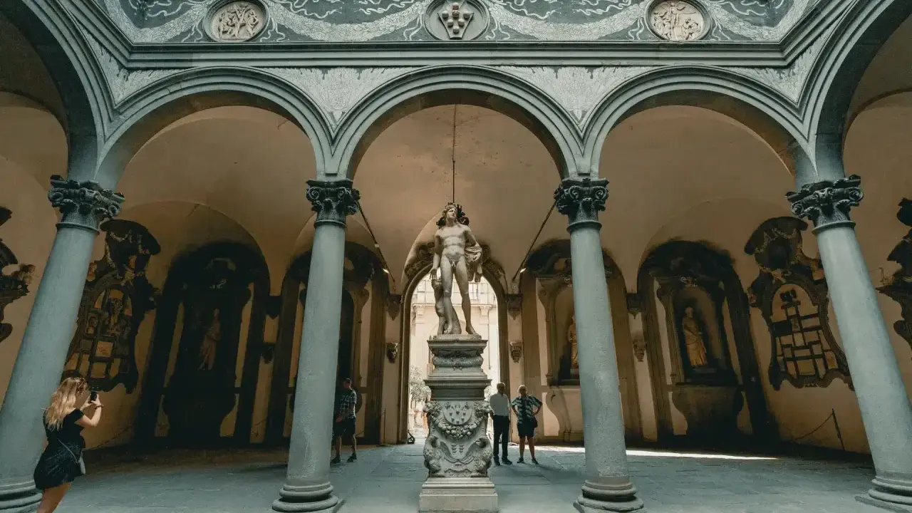 Cour intérieure de Florence avec une statue antique au centre. Une femme prend une photo de la statue florence.