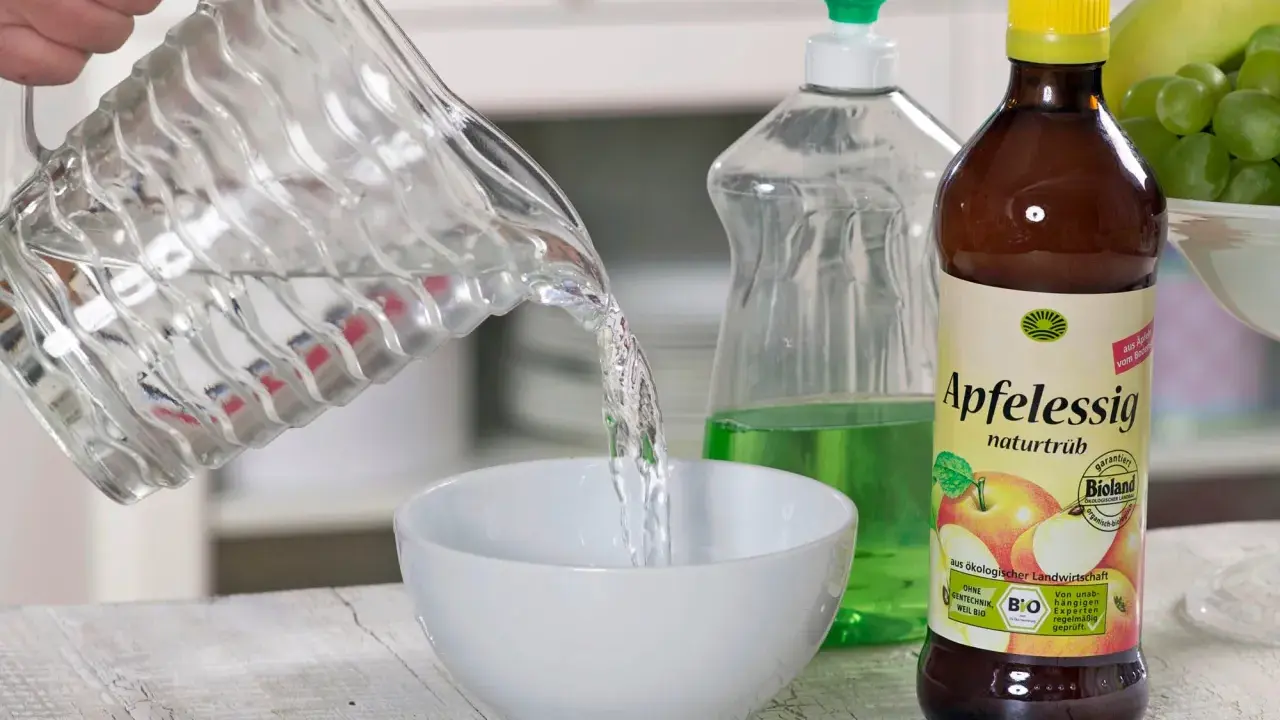 Wasser wird in eine Schüssel gegossen, um eine Fruchtfliegenfalle zu bauen. Apfelessig und Spülmittel sind bereit.