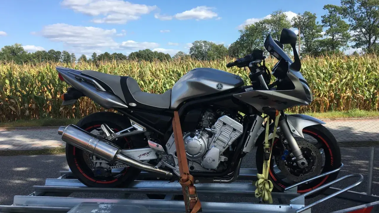 Srebrny motocykl na przyczepce, gotowy do transportu. Może to być związane z akcyzą na motocykle, która wpływa na koszty zakupu.