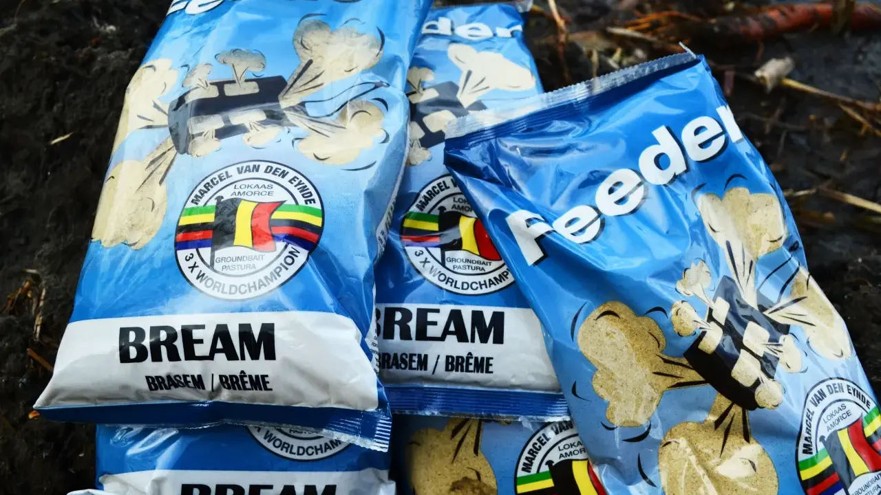 Kilka opakowań zanęt na leszcza "Feeder" z wizerunkiem belgijskiej flagi i napisem "3 x World Champion".