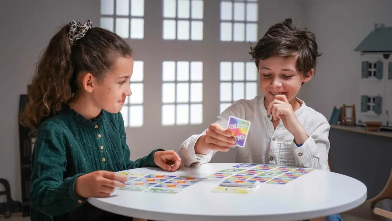 Deux enfants jouent à un jeu de cartes coloré, une belle illustration d'activités sans écran pour adultes et enfants.