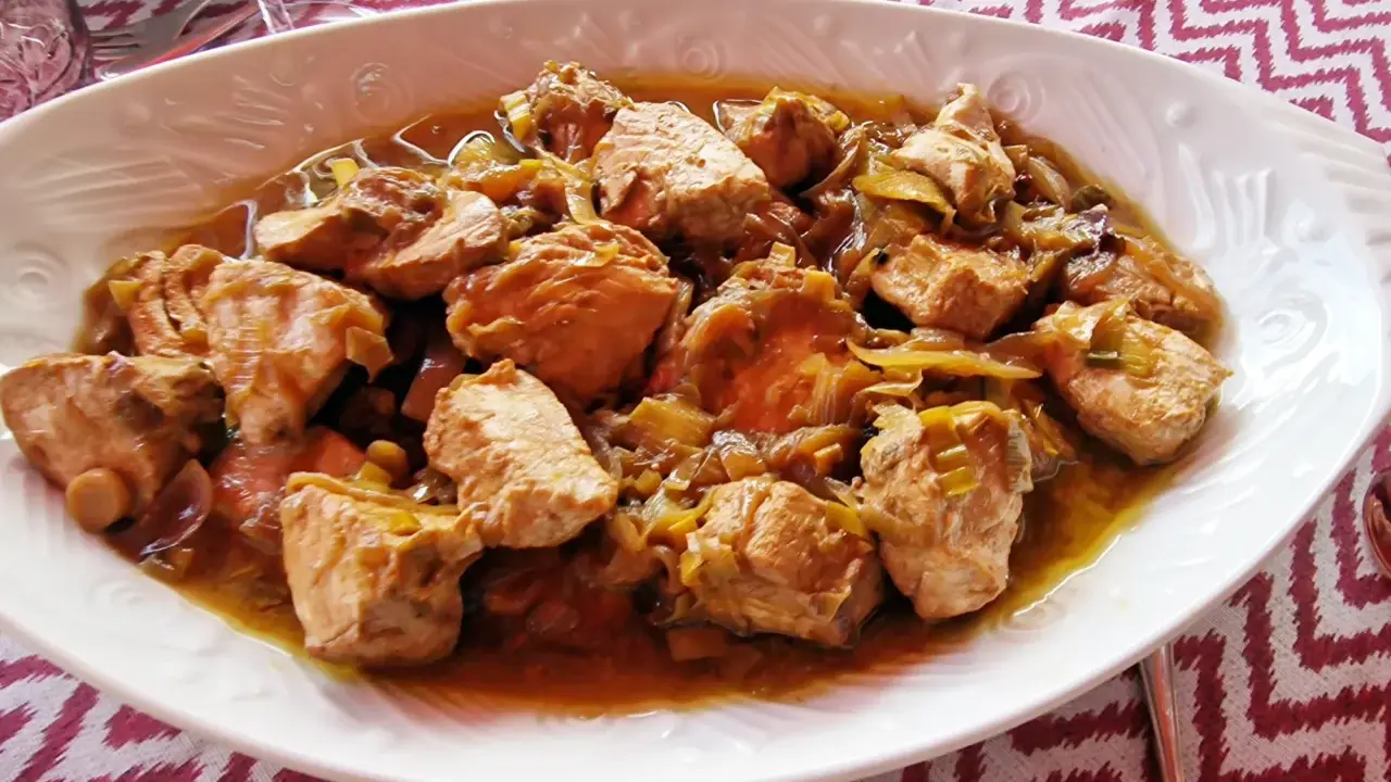 Sabroso bonito en escabeche, trozos de pescado tierno con cebolla en una salsa dorada.