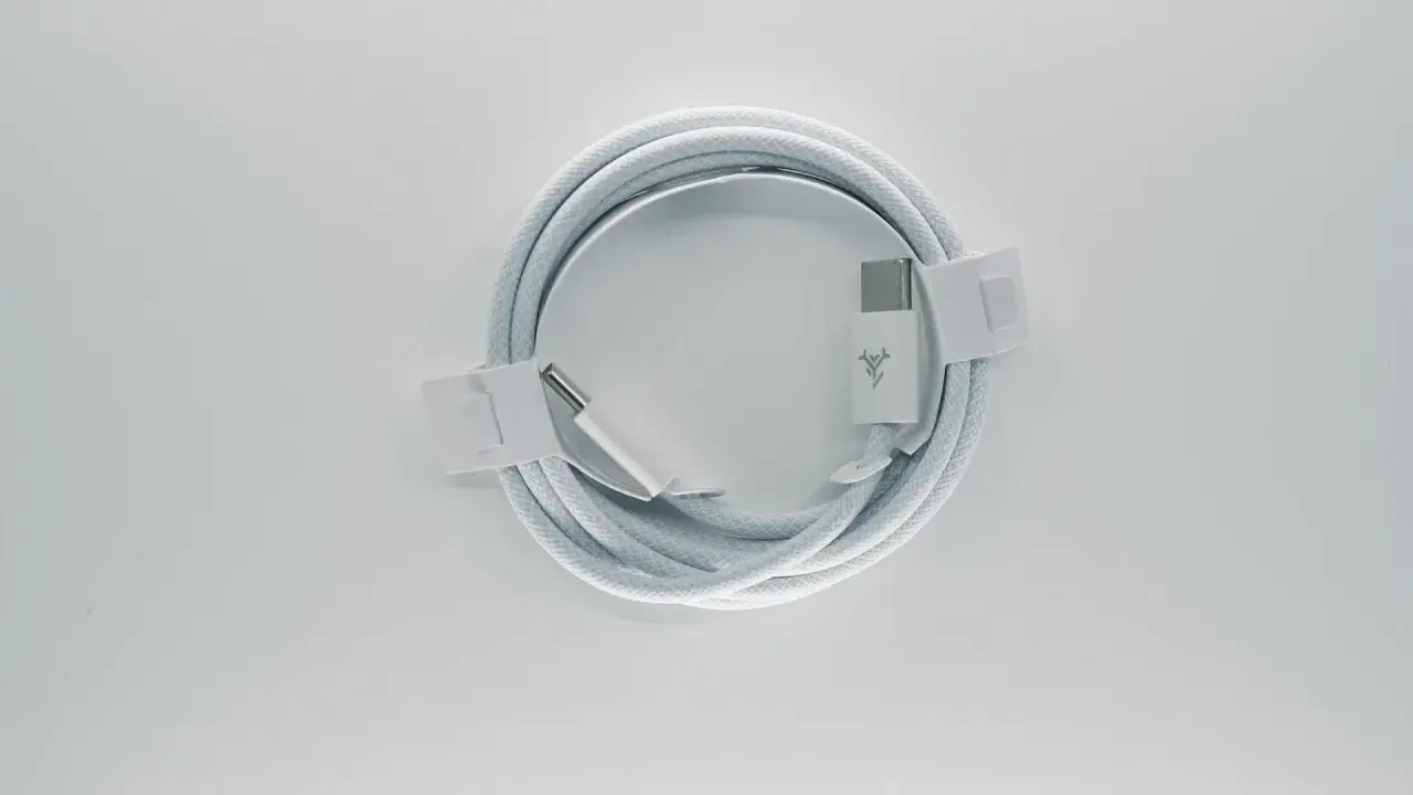 Biały kabel usb typu c, zwinięty w okrąg, z metalowymi końcówkami i logo producenta.