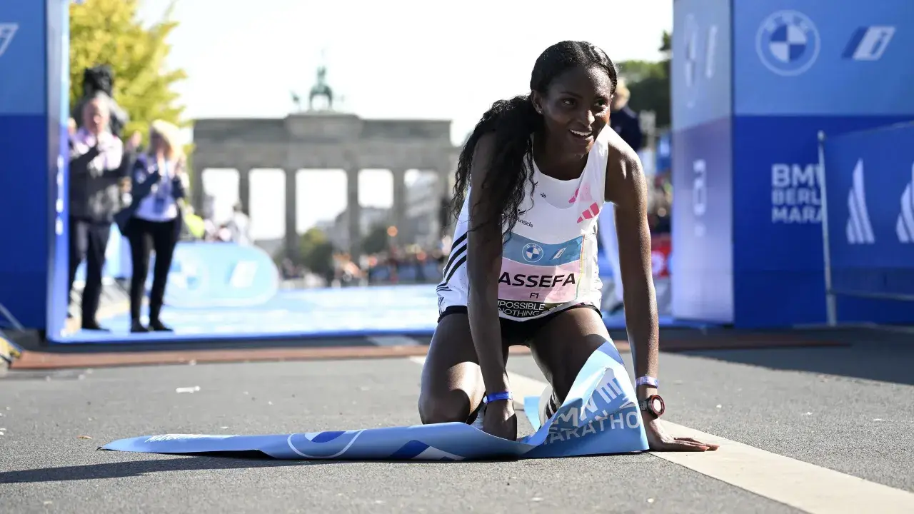 Glückliche Ruth Chepngetich kniet am Ziel des Berlin Marathons, die Ziellinie überquert.