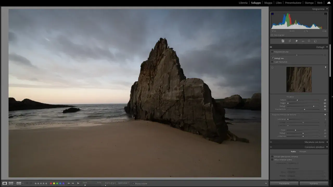 Scogliera imponente su una spiaggia al tramonto, con onde mosse. L'aggiornamento Lightroom sta migliorando i dettagli dell'immagine.