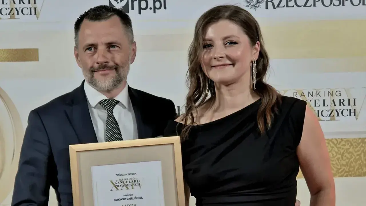 Mężczyzna i kobieta odbierają nagrodę w ramce z napisem "Ranking Kancelarii Prawniczych".
