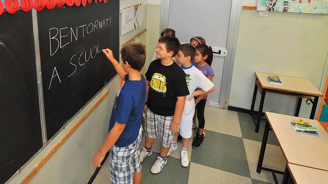 Schulkinder stehen vor einer Tafel mit der Aufschrift "Bentornati a scuola". Sie warten gespannt, wie viele Schultage ein Jahr hat.
