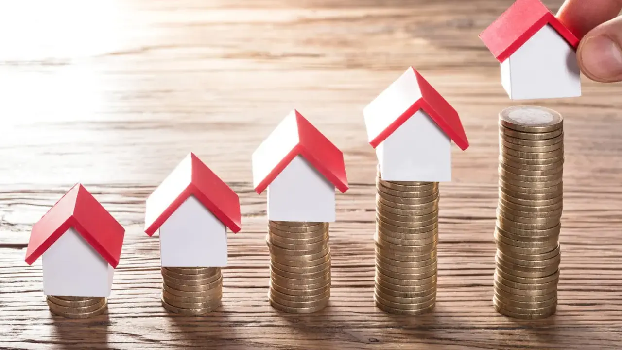 Cinq maisons miniatures sur des piles de pièces, symbolisant une augmentation du loyer sur 3 ans.