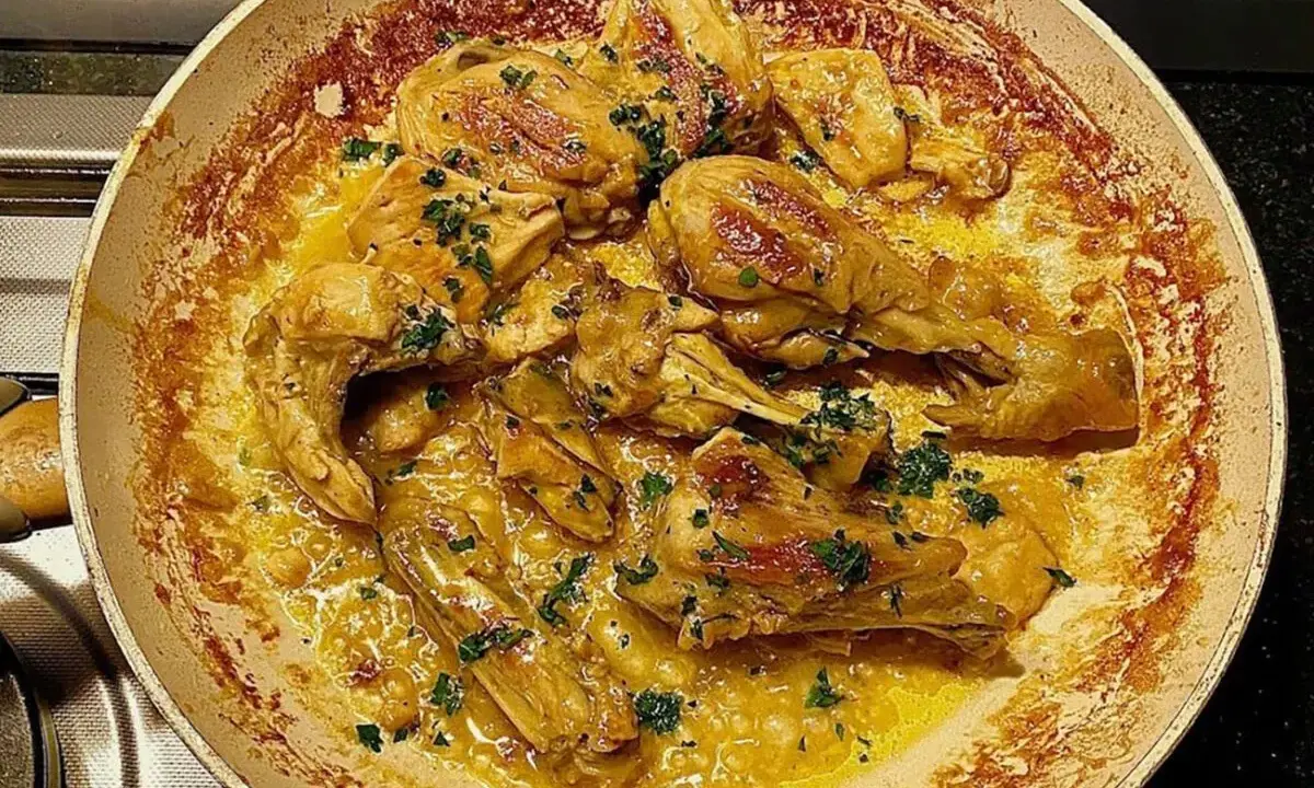 Succulento pollo alla marengo in padella, con erbe aromatiche fresche e una ricca salsa dorata.