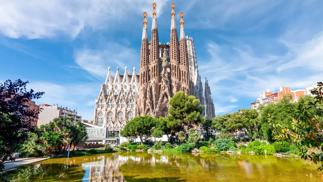 La Sagrada Familia, con le sue torri svettanti e il riflesso sull'acqua, sembra un sogno che attende il suo completamento. Chissà quando finirà la Sagrada Familia.