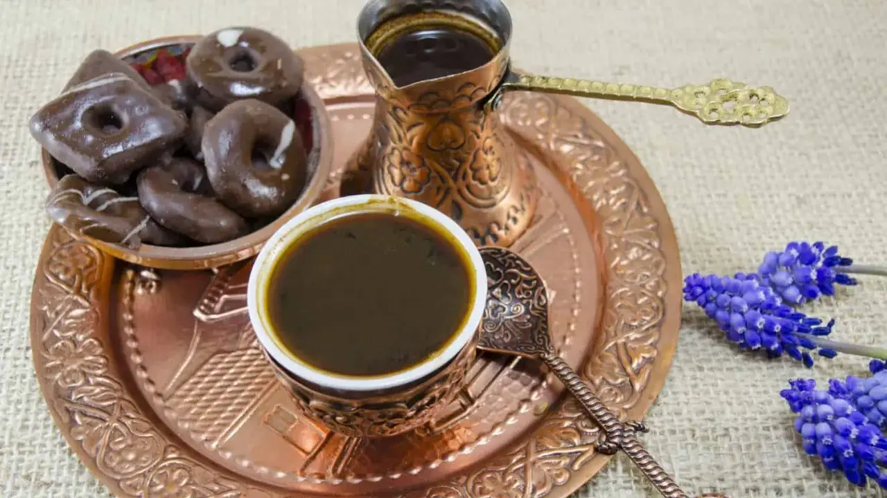 Ein traditionelles Mokkakännchen mit starkem Kaffee, dazu Schokoladenkekse und blaue Blumen. Was ist Mokka? Ein Genuss für die Sinne.