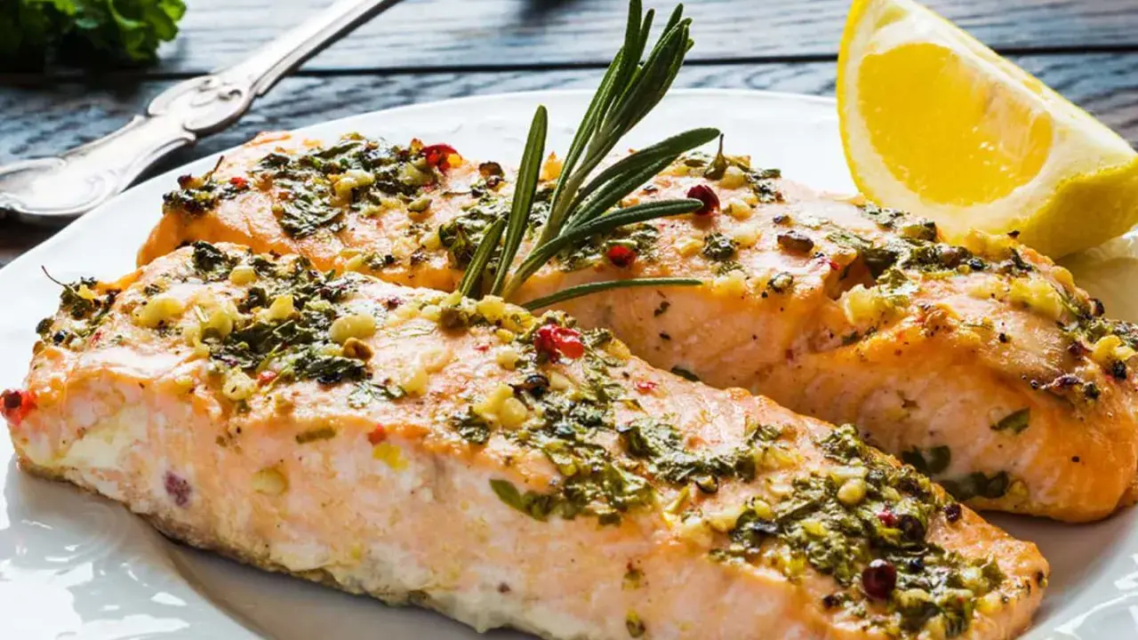 Två saftiga laxfiléer med en härlig pesto-topping, garnerade med rosmarin och en citronklyfta.