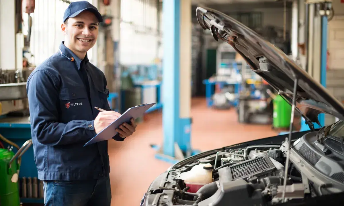 Uśmiechnięty mechanik notuje przebieg auta przed pierwszą wymianą oleju w silniku 1.5 TSI.