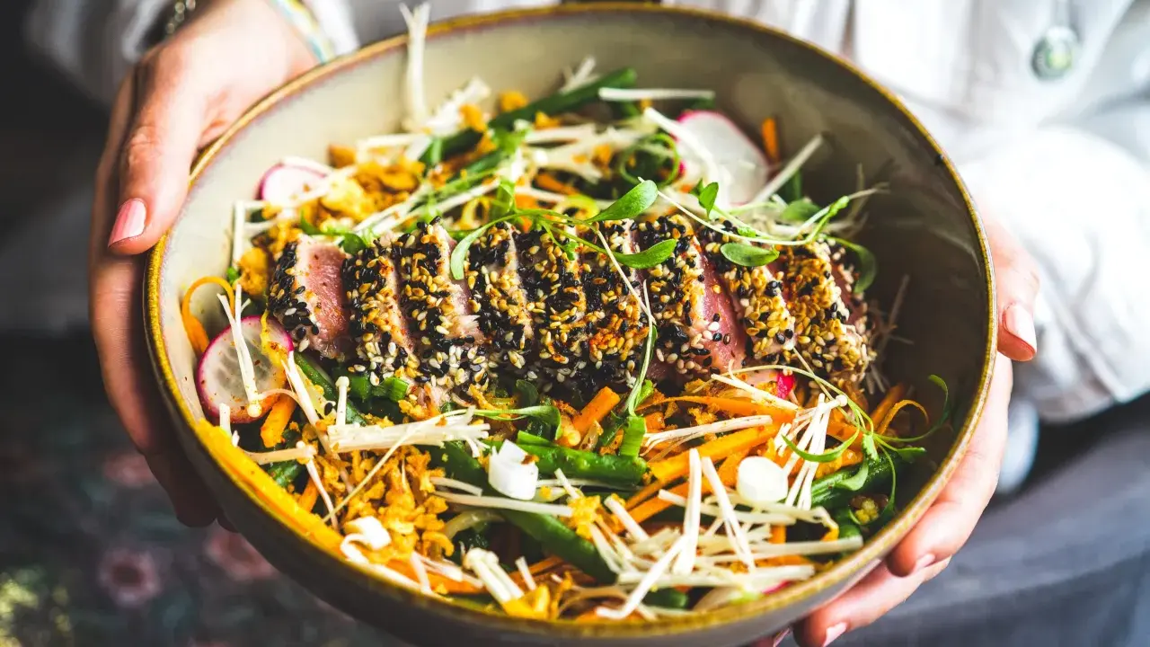 Un délicieux tataki de thon, enrobé de sésame noir et blanc, repose sur un lit de légumes croquants : haricots verts, carottes râpées, radis et champignons enoki.