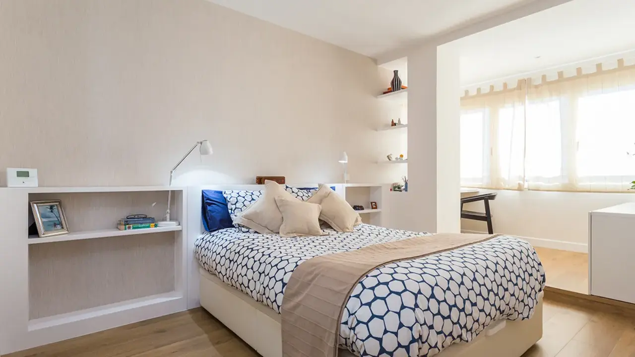 Habitación moderna con cama, estanterías y una apertura que permite tirar tabique para unir dos habitaciones.