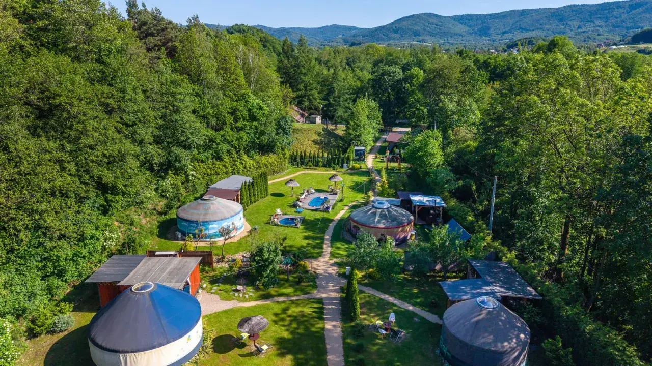 Malowniczy aloha glamp z jurtami, basenami i zielonymi wzgórzami w tle. Idealne miejsce na relaks.