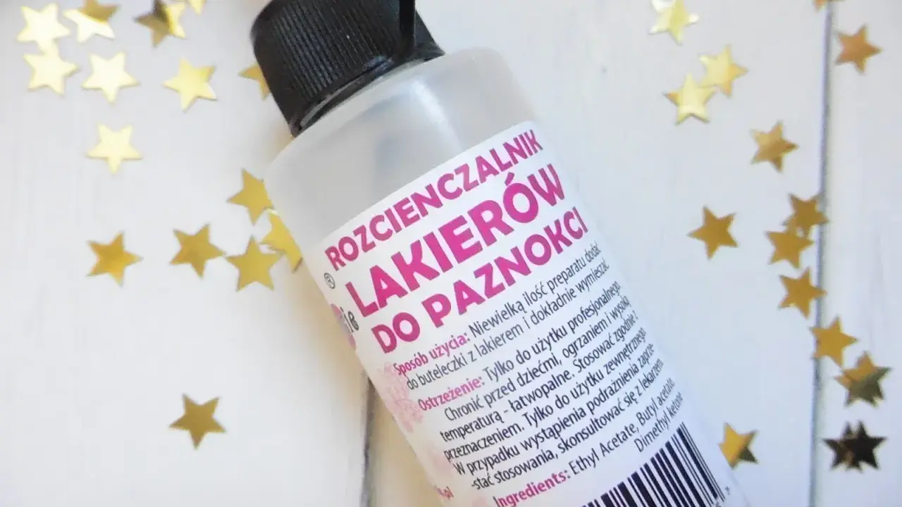 Butelka rozcieńczalnika do lakierów do paznokci z czarną zakrętką i złotymi gwiazdkami.