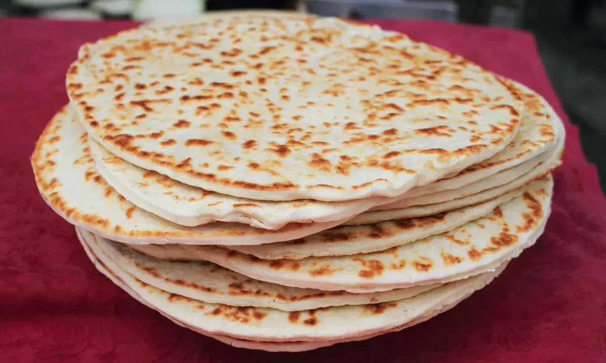 Una pila di piadine dorate, appena sfornate, con macchie di cottura che invitano a gustare questo classico della cucina romagnola.