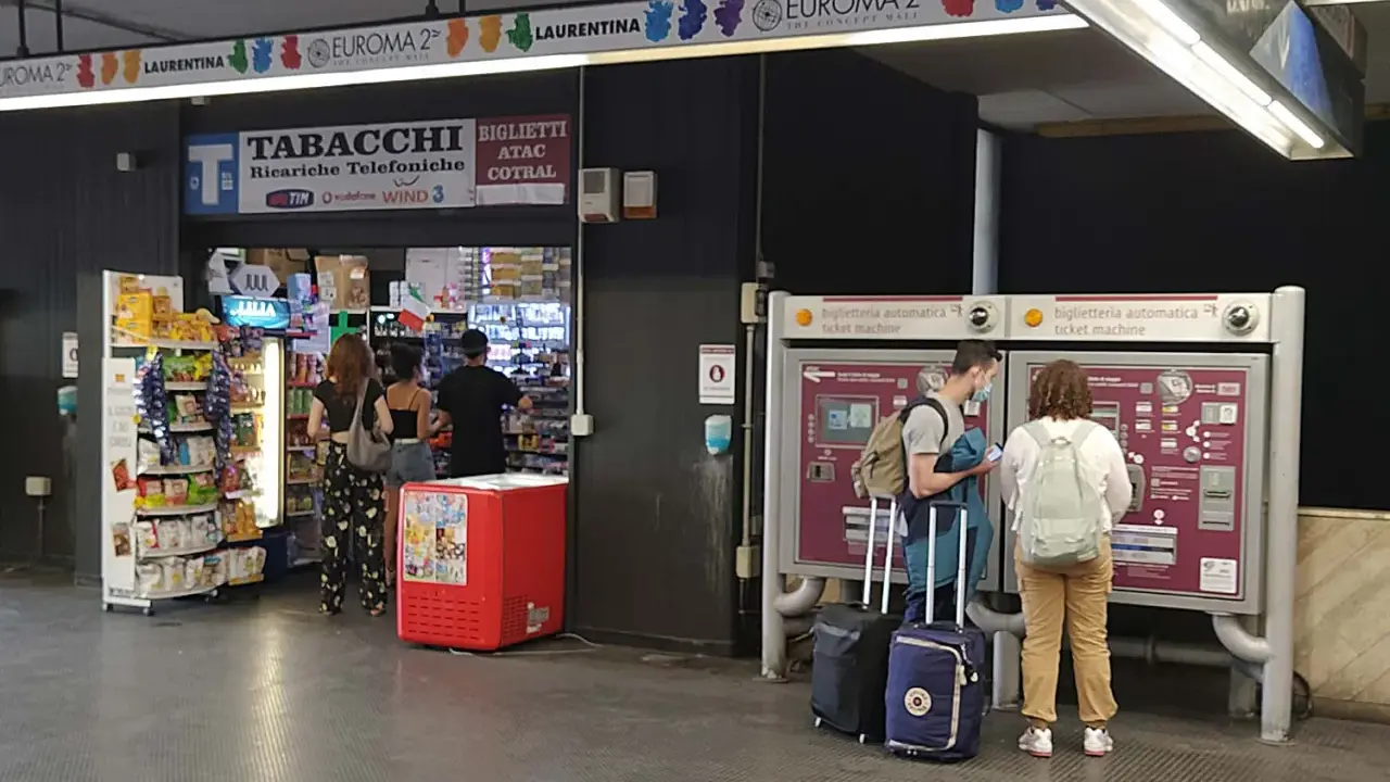 Przystanek autobusowy w Rzymie Ciampino. Ludzie kupują bilety i artykuły w sklepie.