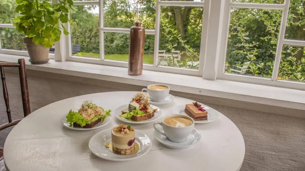 Fika på ett mysigt cafe i Skåne med smörgåsar, tårtor och kaffe.