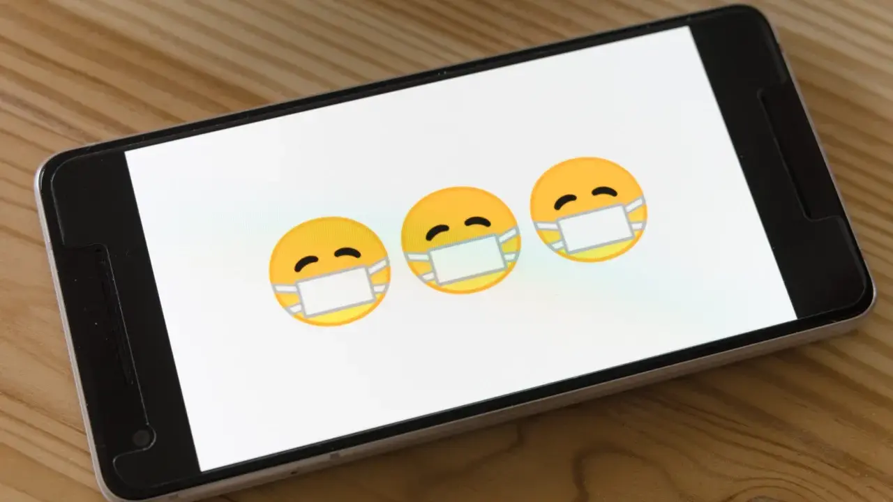 Trzy emoji w maseczkach na ekranie smartfona. Dowiedz się, jak usunąć wirusy z iPhone.