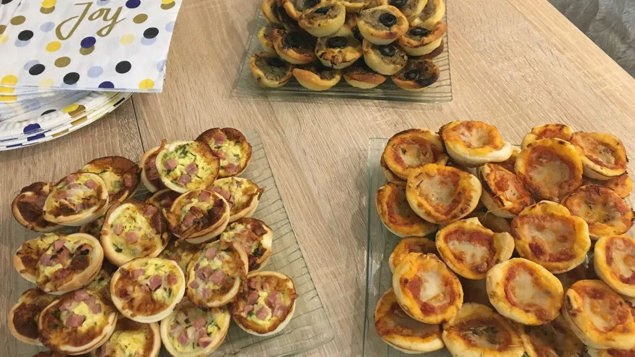 Plateaux de mini-pizzas et quiches, parfaits pour une idée repas crémaillère conviviale.