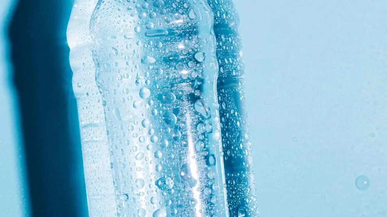 Krople wody na plastikowych butelkach, sugerujące, czy można zamrozić wodę w butelce plastikowej.