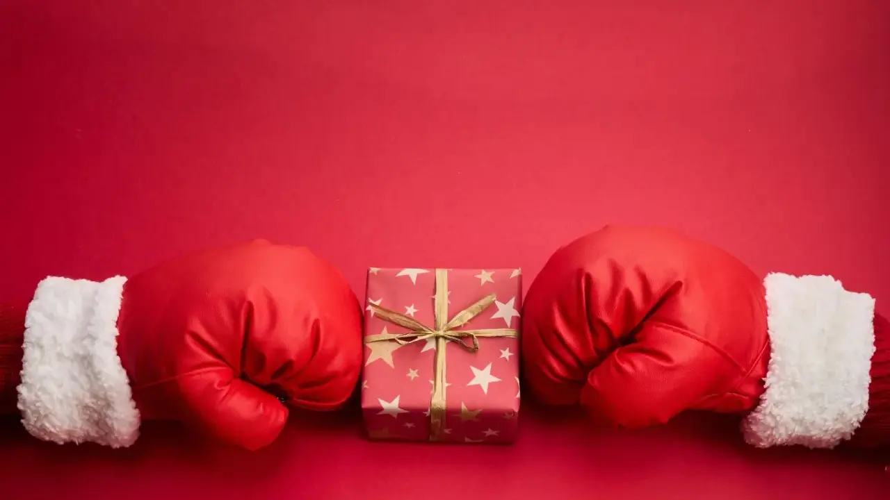 Rękawice bokserskie w świątecznym stylu otaczają prezent. Czy to zapowiedź, boxing day co to znaczy?