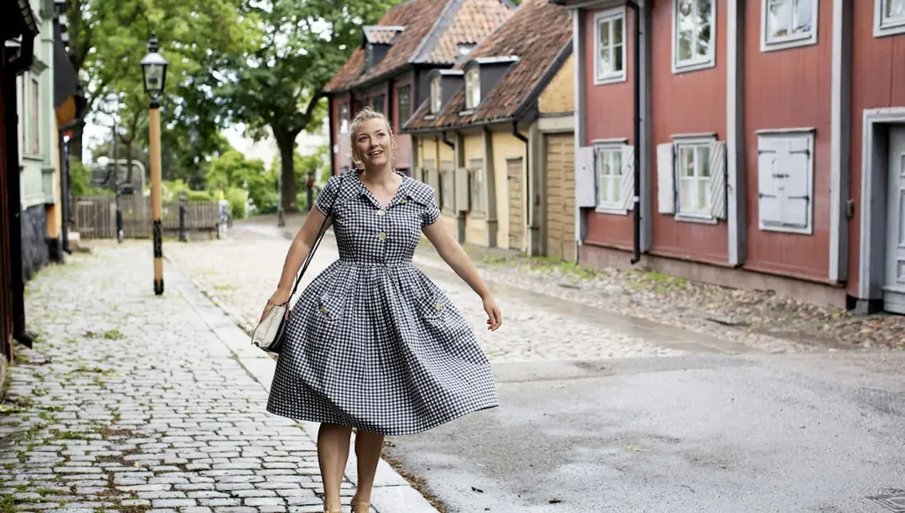 Kvinna i rutig klänning på kullerstensgata, inspirerad av Elsa Billgrens blogg.