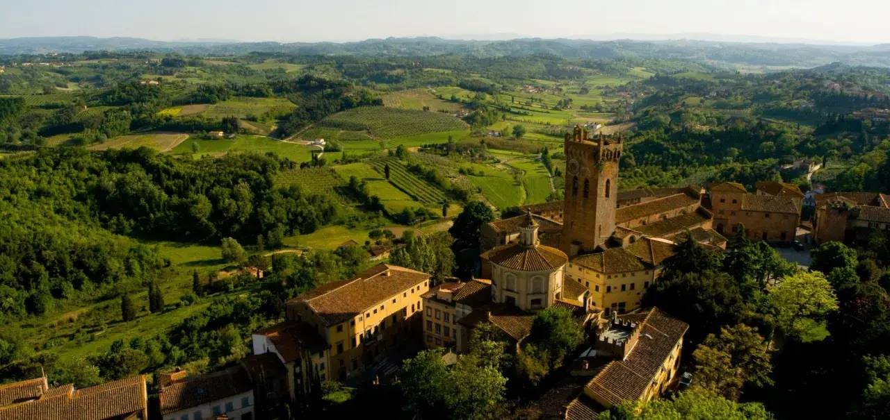 Un borgo medievale con una torre svetta tra le verdi colline pisane, un paesaggio da cartolina.