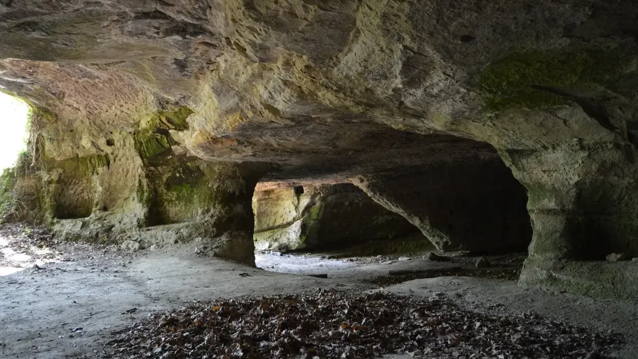 L'interno di una grotta scavata nella roccia, con nicchie e passaggi che ricordano Vitozza, la città perduta.