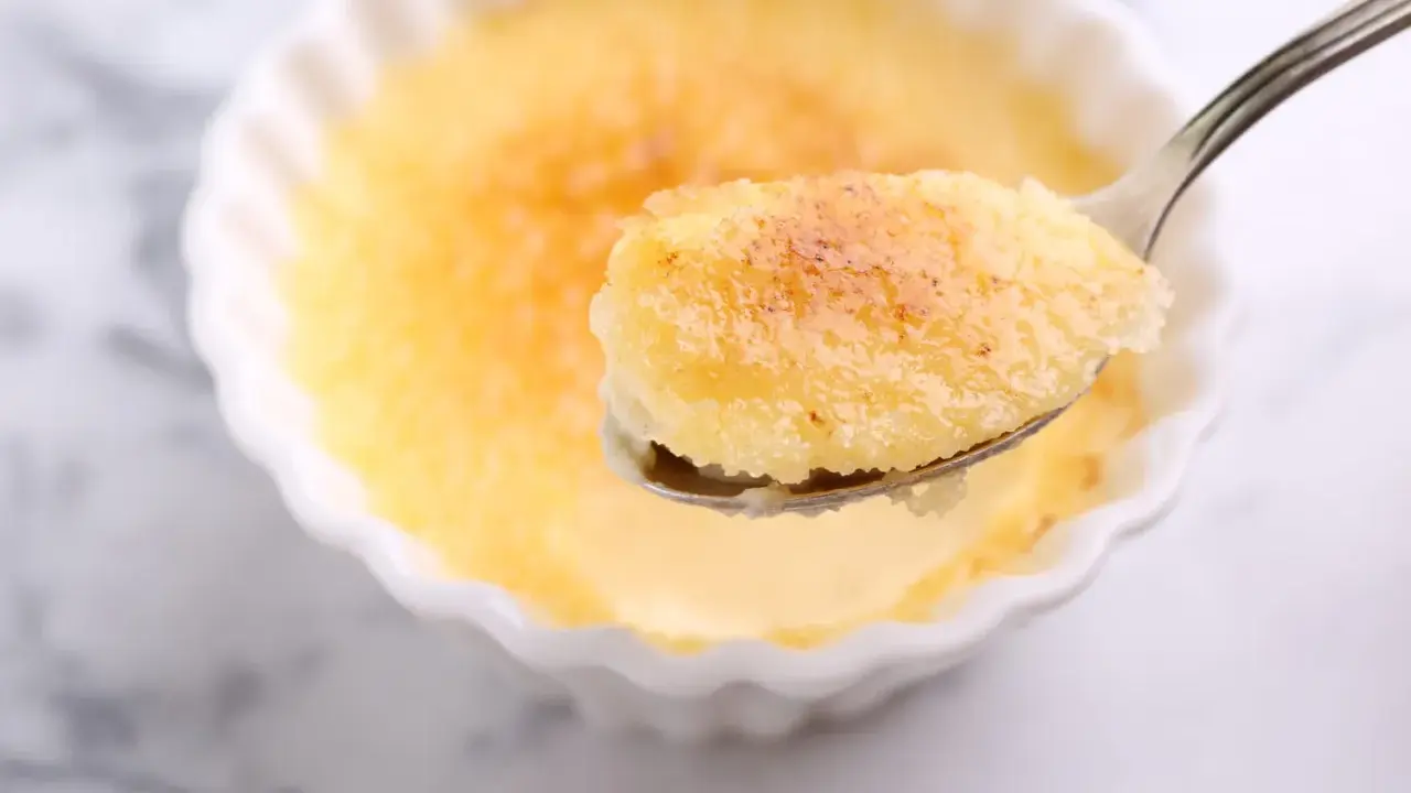 Une cuillère de semoule au lait et aux œufs, avec sa croûte caramélisée dorée, prête à être dégustée.