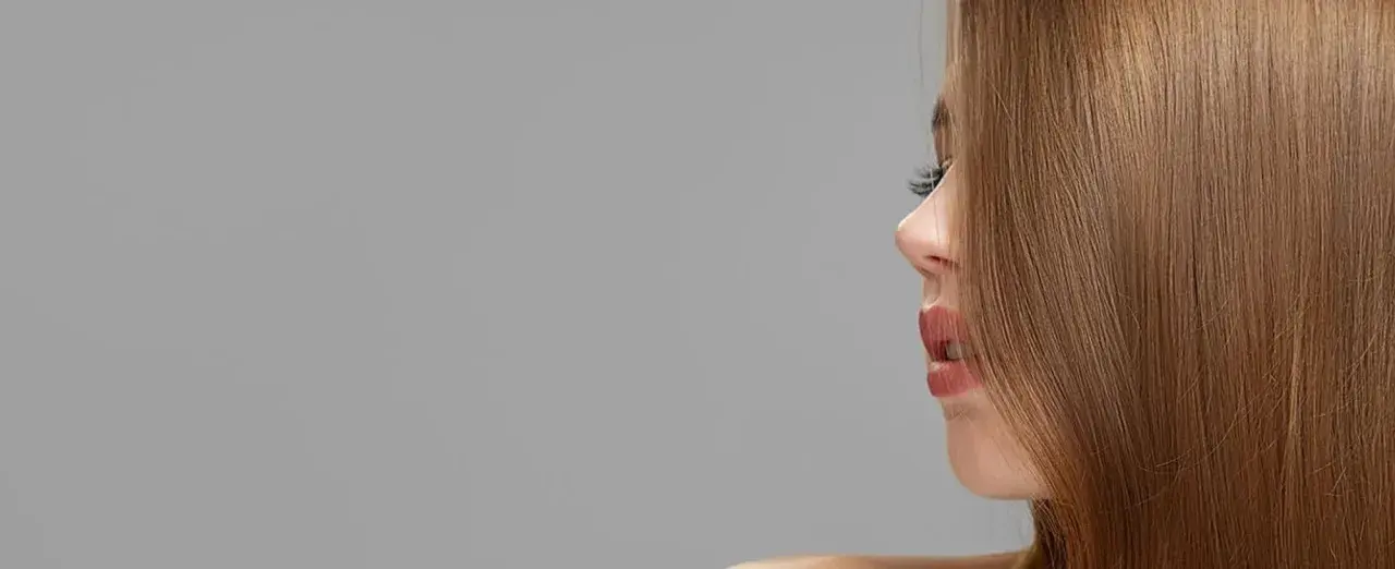 Ein Profil einer Frau mit glänzendem, kupferblondem Haar. Die Haarfarbe schimmert warm und natürlich.