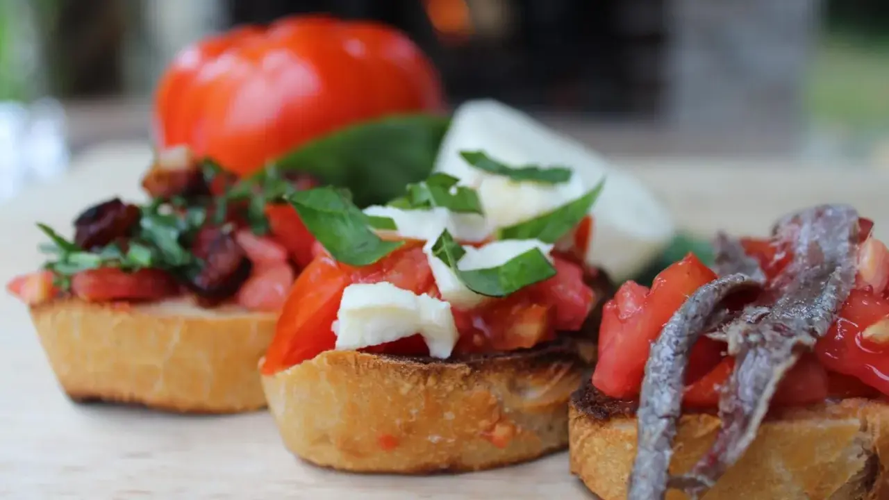Drei italienische Bruschetta mit Tomaten, Mozzarella und Sardellen auf geröstetem Brot.
