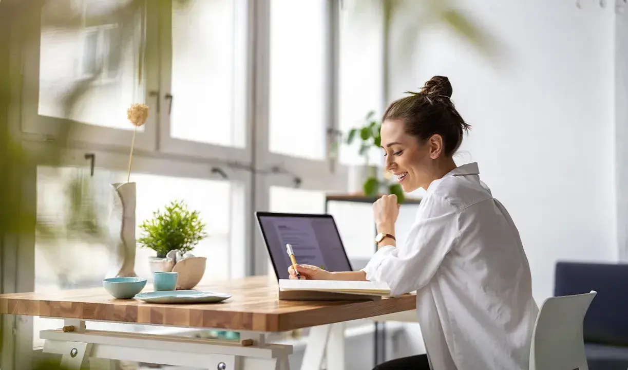 Uśmiechnięta kobieta pracuje przy laptopie, planując swój **ecommerce dropshipping**. Sukces w biznesie online!