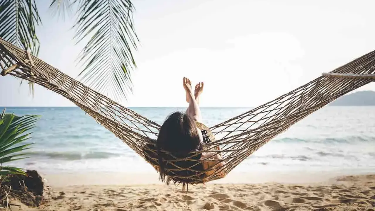 Relaks na plaży w hamaku, idealny opis wakacji po angielsku. Słońce, morze i palmy tworzą rajski widok.