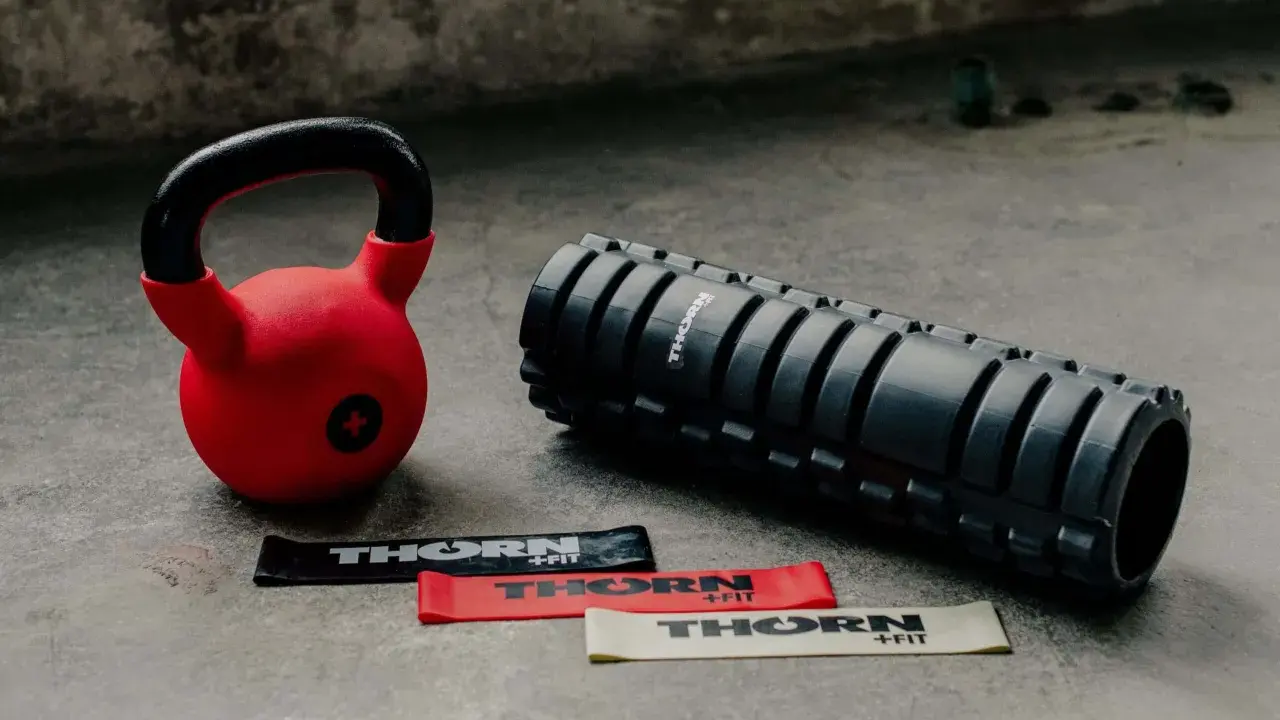 Czerwony kettlebell, wałek do masażu i taśmy oporowe. Idealny zestaw, by zacząć treningi z kettlebell.