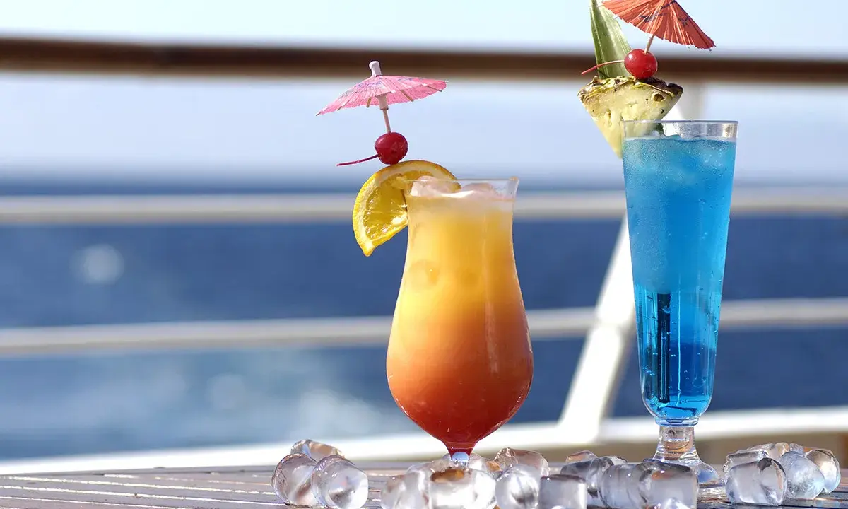 Due cocktail colorati, un tramonto e un blu intenso, decorati con ombrellini e frutta, perfetti per godersi i pacchetti bevande MSC in crociera.