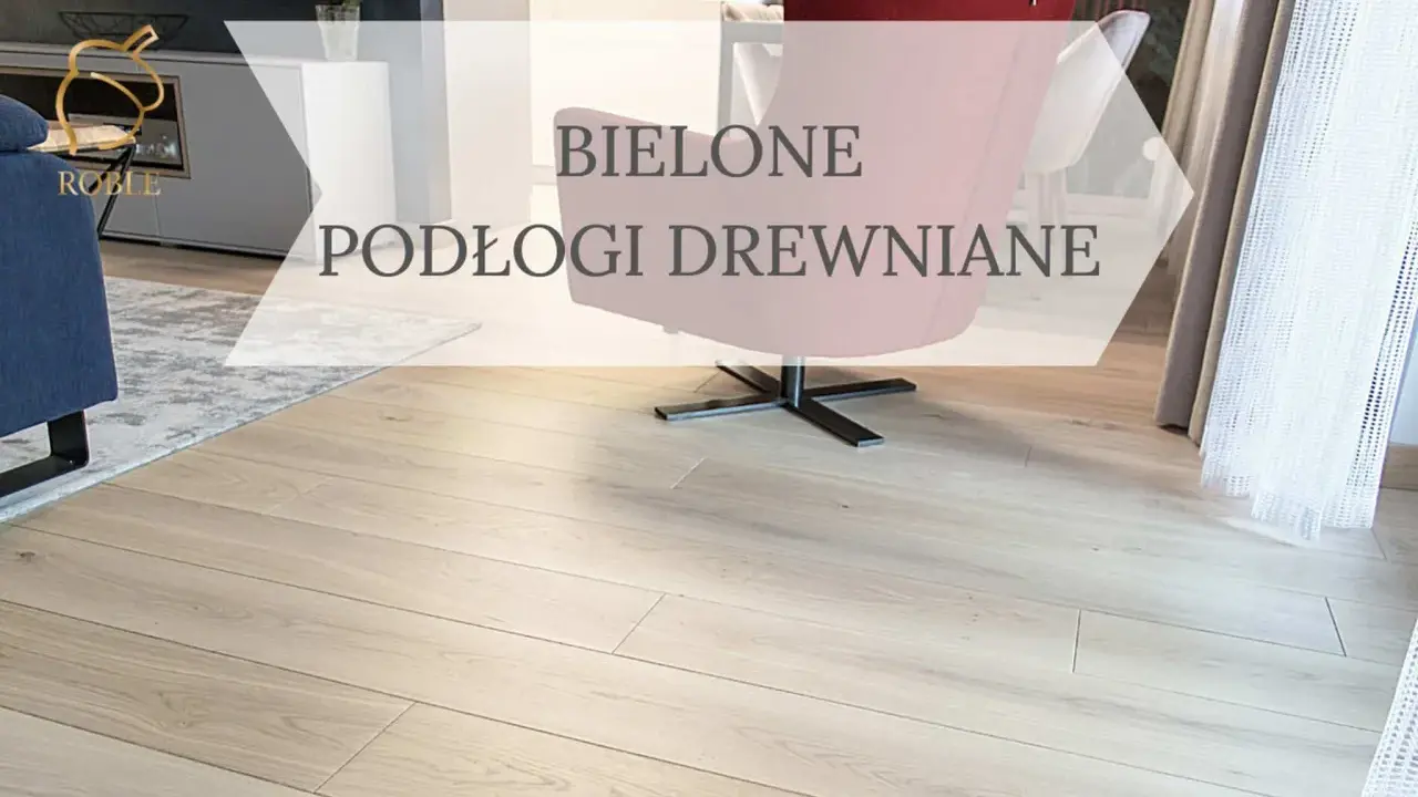 Jasne, bielone drewno na podłodze w salonie, z widocznym fragmentem granatowej kanapy i różowego fotela.