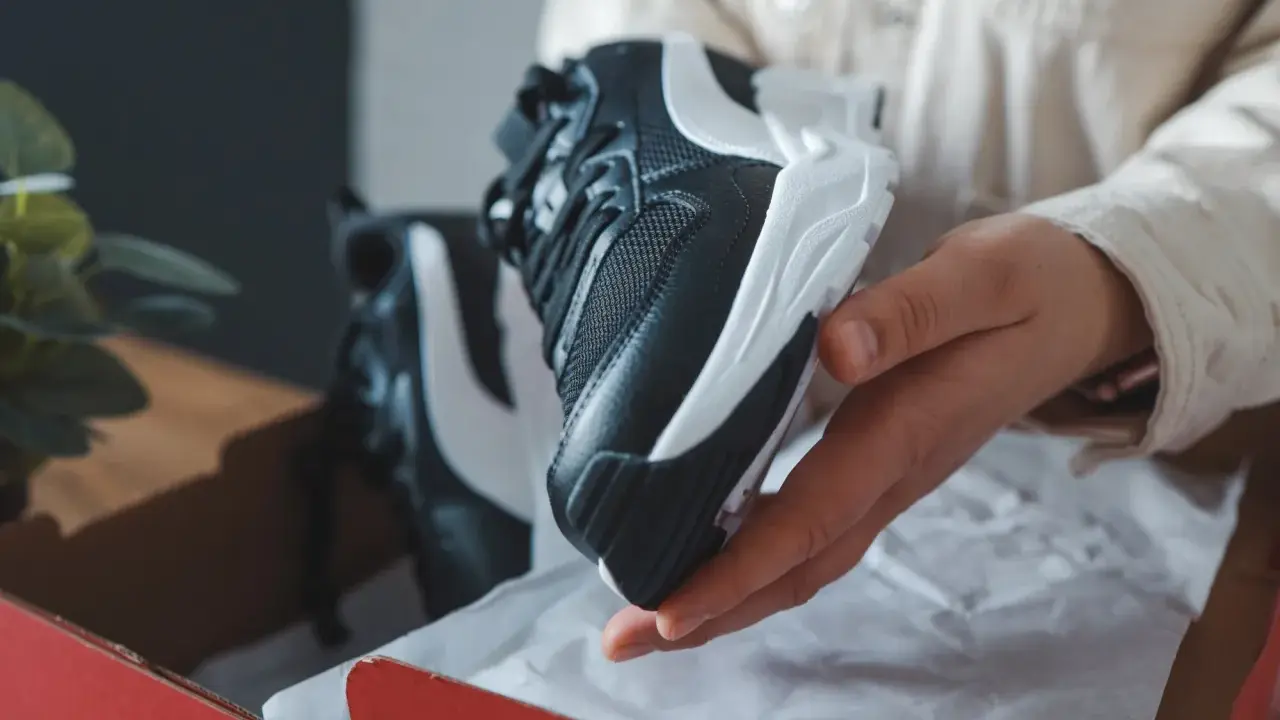 Schwarze und weiße Sneaker, die aus einer roten Box genommen werden. Sehen sie aus wie vapormax fake?