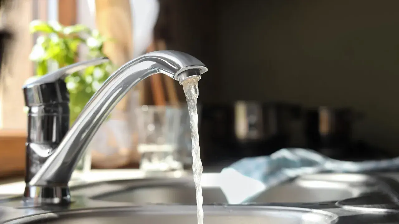 Wasserhahn mit integriertem Durchlauferhitzer, Testsieger. Wasser fließt aus dem Hahn in die Spüle.
