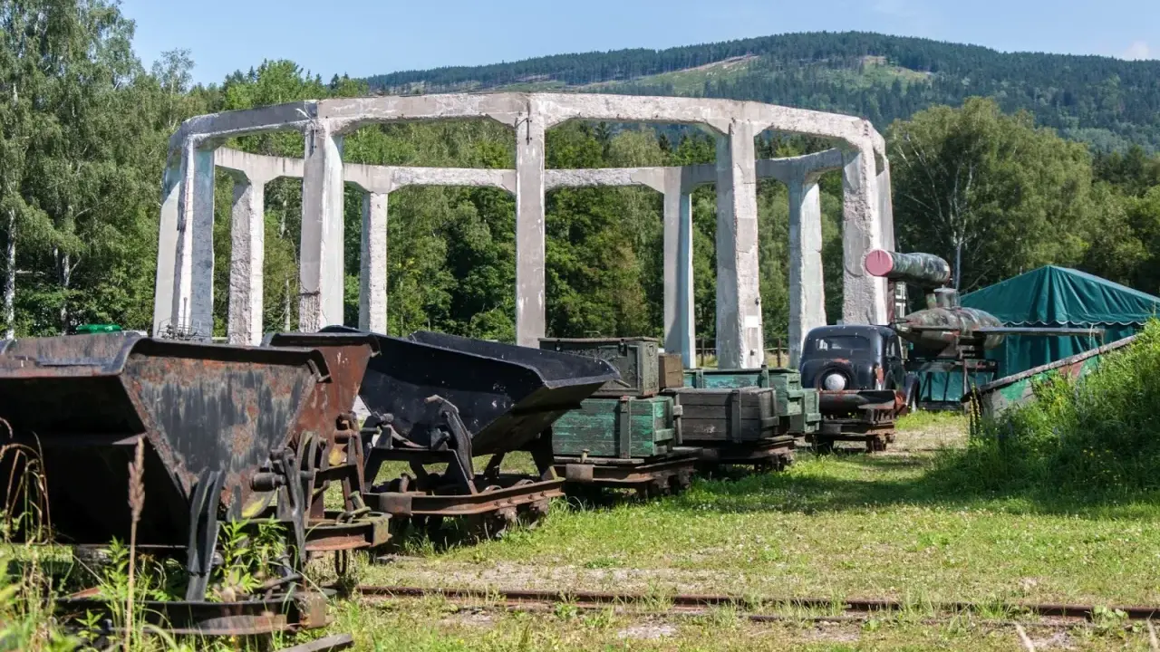 Ruiny budowli w muzeum molke, obok stare wagony kopalniane, ciężarówka i zielony namiot.