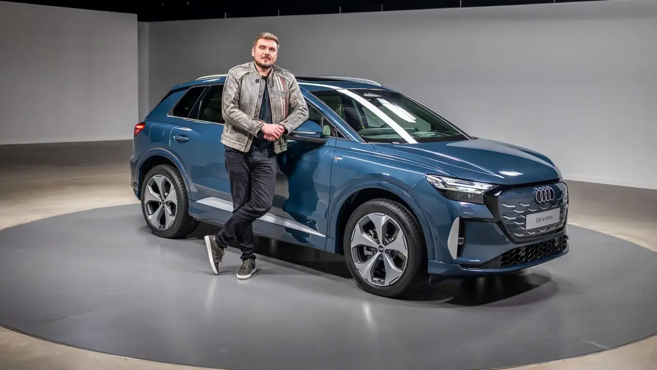 Ein Mann lehnt lässig an einem blauen Audi Q4 e-tron 2026.