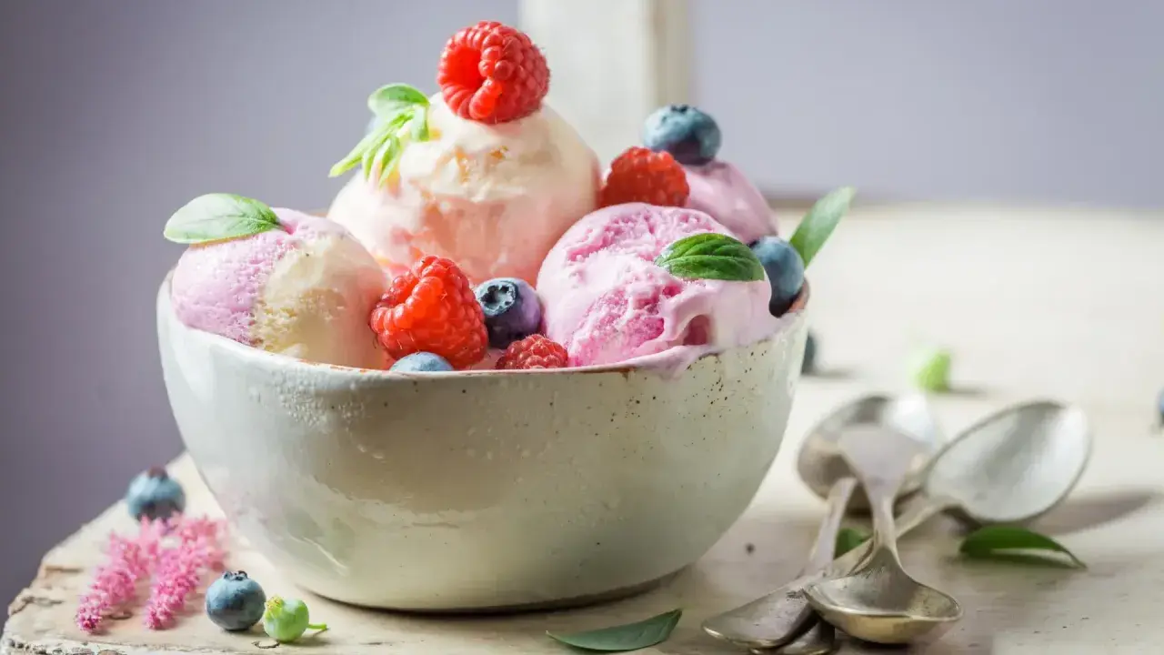 Deliciosos helados caseros de fresa y vainilla, adornados con frambuesas y arándanos frescos.