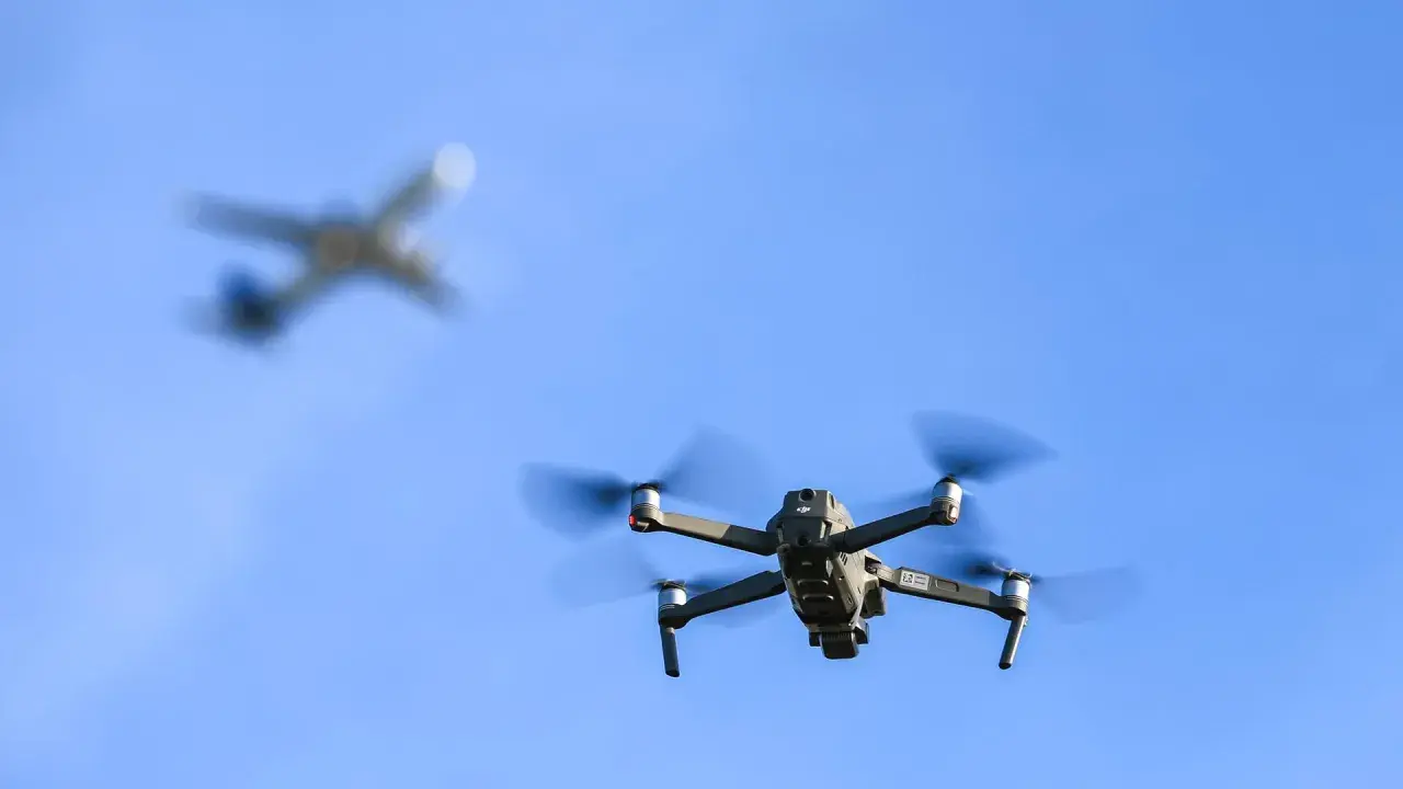 Drohne im Flug, während ein Flugzeug im Hintergrund verschwimmt. Informiere dich über Länder, in welchen Ländern Drohnen verboten sind, bevor du abhebst.