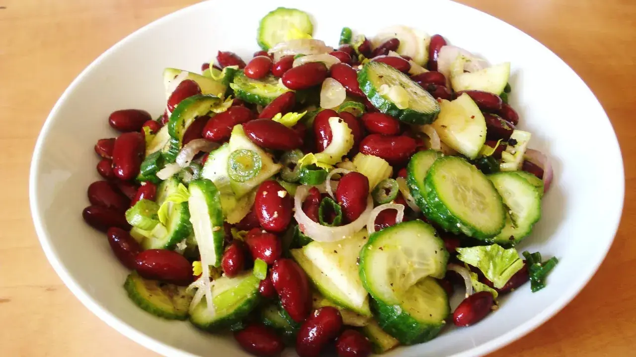 Salade colorée de haricots rouges, concombre, oignon rouge et céleri, prête à être dégustée.