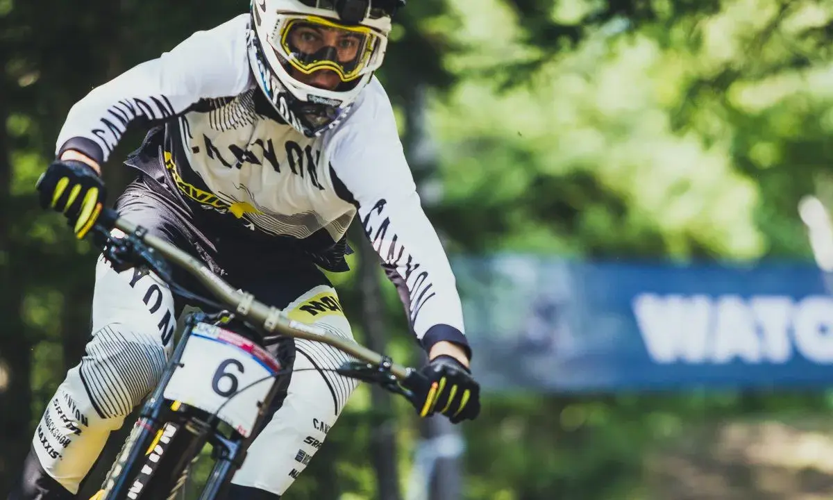 Downhill-Fahrer Mark Wallace in voller Fahrt, mit Helm und Brille, bereit für die nächste Herausforderung.