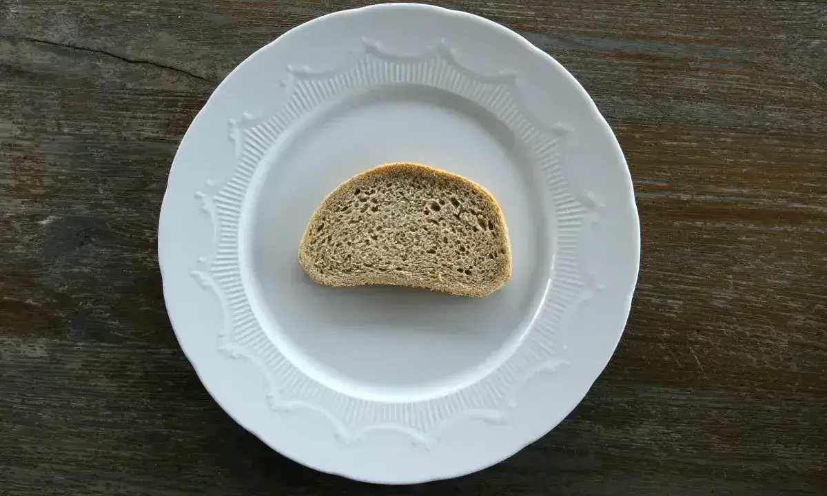 Jedna kromka chleba na białym talerzu. Zastanawiasz się, ile g ma kromka chleba?