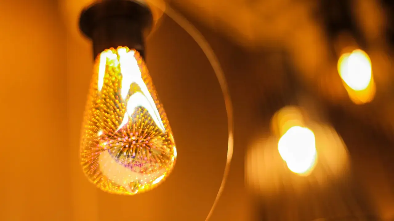 Une ampoule décorative aux filaments lumineux, projetant une lumière chaude et dorée. L'étiquette ampoule est subtilement intégrée dans le design.